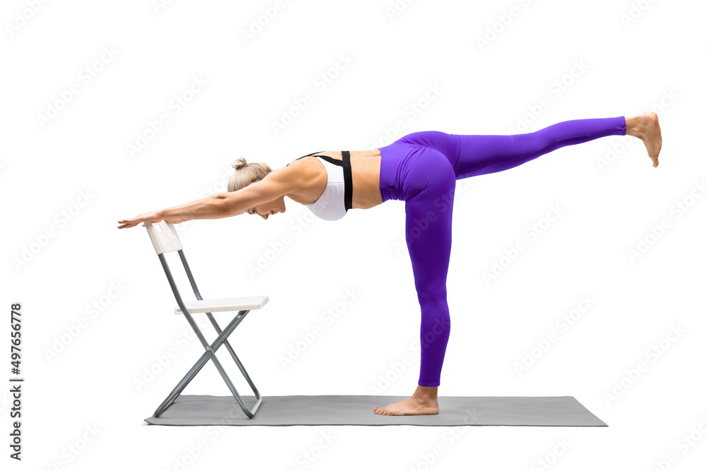 Iyengar yoga balance. Fit caucasian woman in purple leggings practice  warrior pose III using a chair, Virabhadrasana III, isolated on white.  Stock Photo