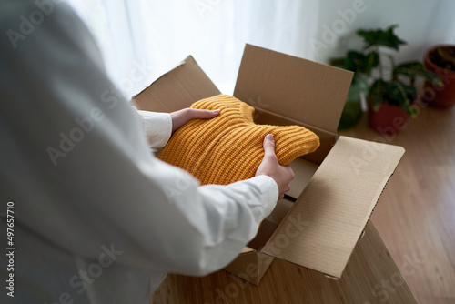 Woman putting sweater in carton box photo
