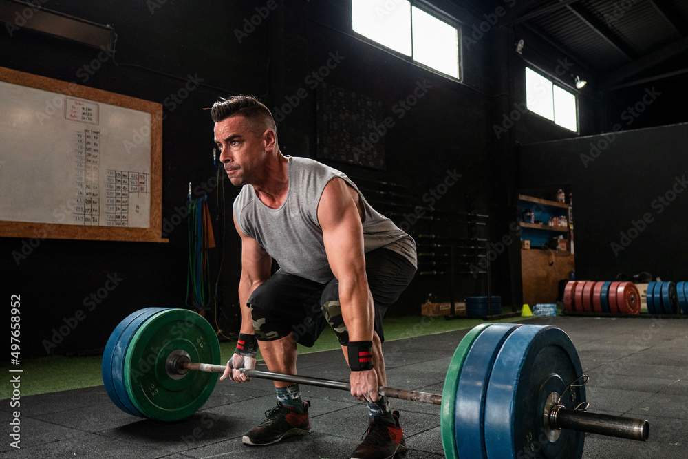 Strong man lifting heavy barbell in gym Strong man lifting heavy barbell in gym