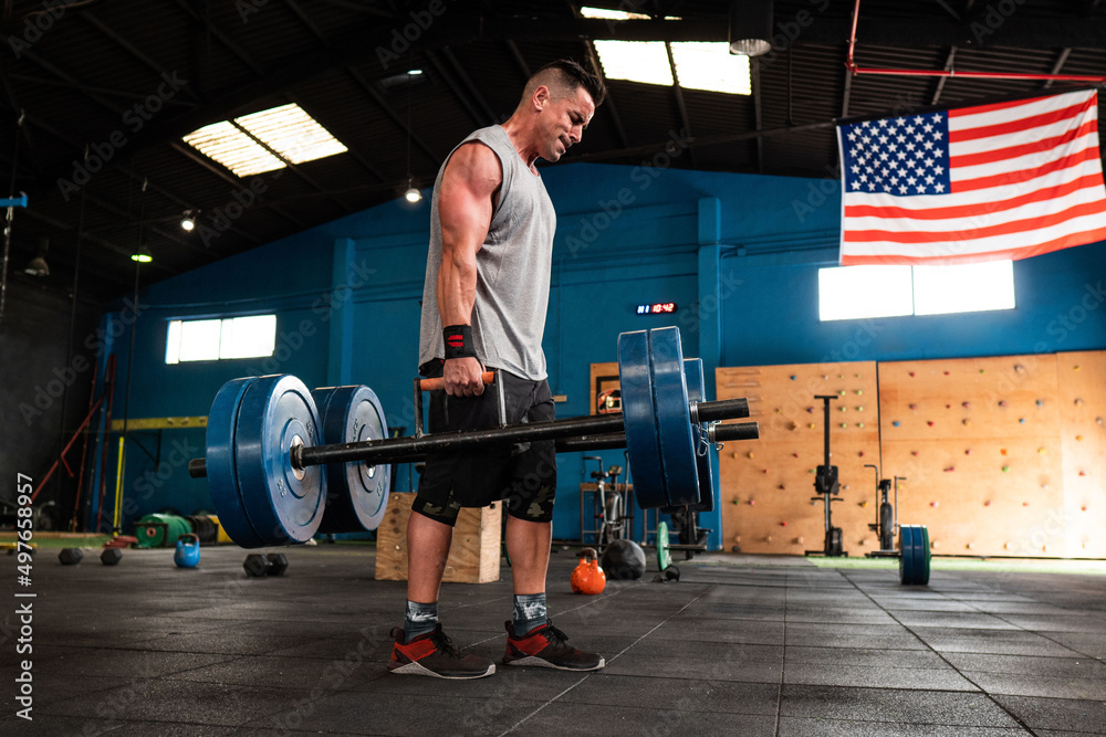 Strong man with heavy barbells in gym Strong man with heavy barbells in gym
