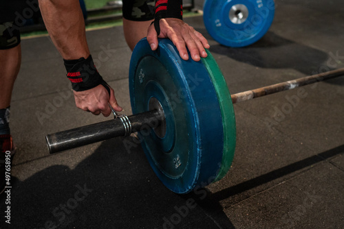 Crop athlete adjusting weights on barbells photo