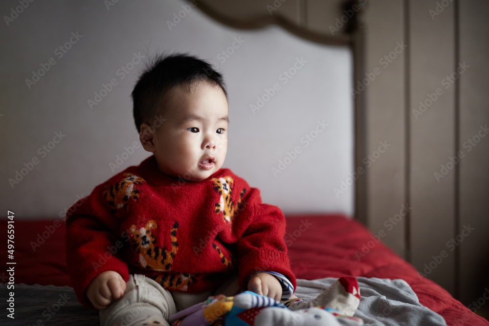 Cute Male Chinese Infant Sitting On A Bed At Home In Anhui, China. Cute Male Chinese Infant Sitting On A Bed At Home In Anhui, China.