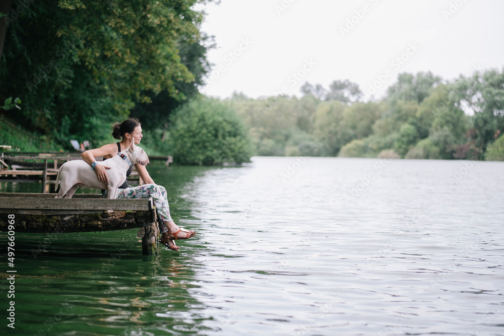 Woman relaxing at a lake with a bullterrier dog Woman relaxing at a lake with a bullterrier dog