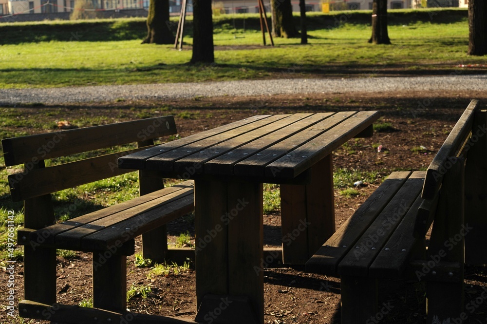 Wooden picnic table with two wooden benches in a park on a sunny day Wooden picnic table with two wooden benches in a park on a sunny day
