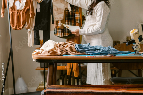 Pregnant woman looking at baby clothes from clothes rack
