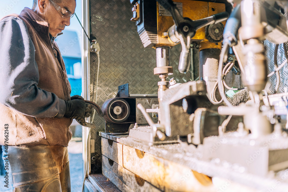Man grinding horseshoe on machine at workbench Man grinding horseshoe on machine at workbench