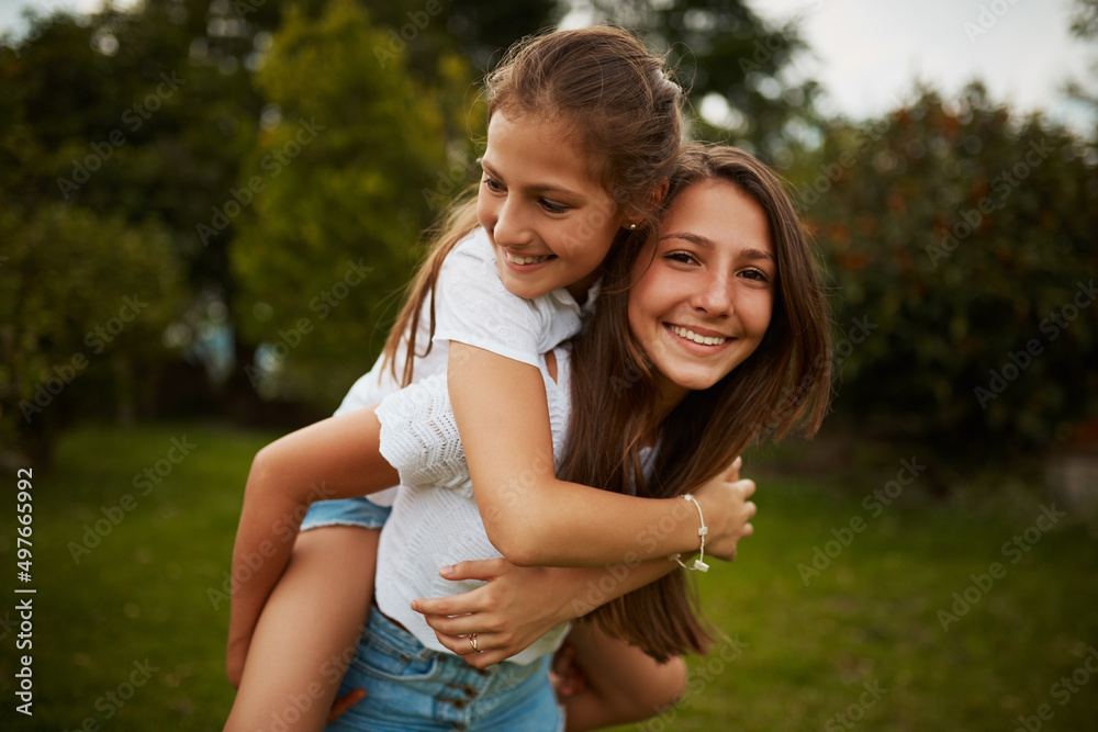 Im her biggest supporter. Cropped portrait of a young girl giving her younger sister a piggyback ride outdoors. Im her biggest supporter. Cropped portrait of a young girl giving her younger sister a piggyback ride outdoors.