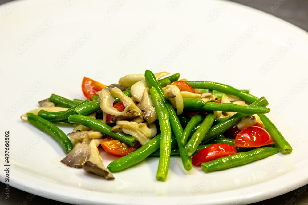 Fried oyster mushrooms with green string beans and tomatoes are on a plate Fried oyster mushrooms with green string beans and tomatoes are on a plate