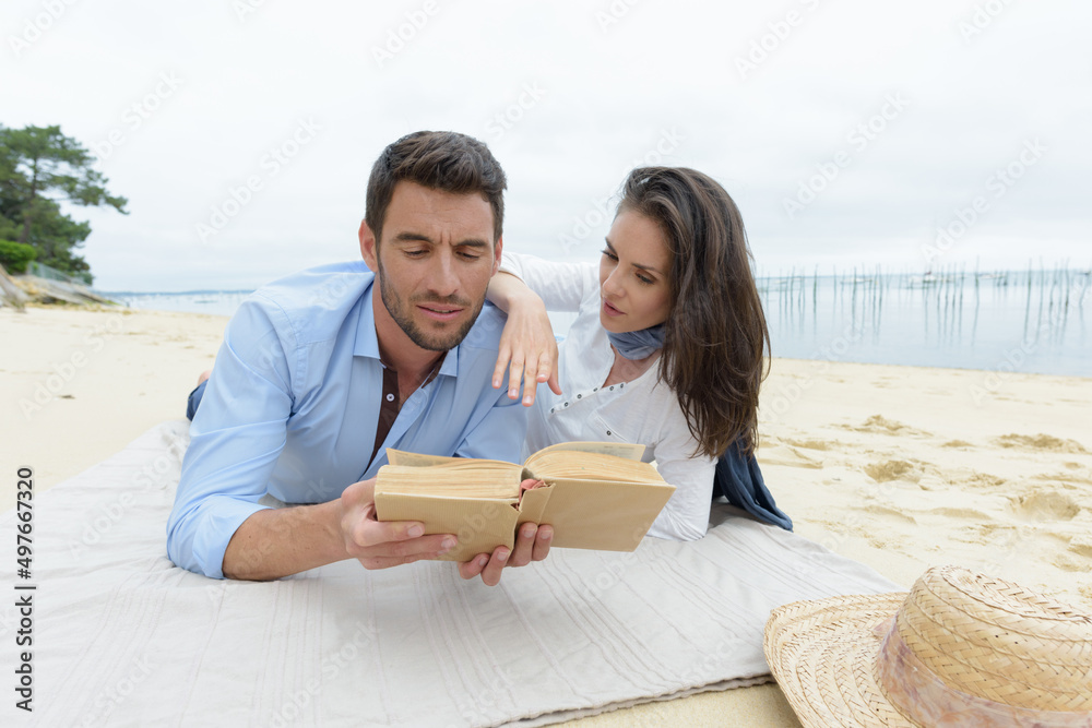 portrait of happy couple reading book on beach portrait of happy couple reading book on beach