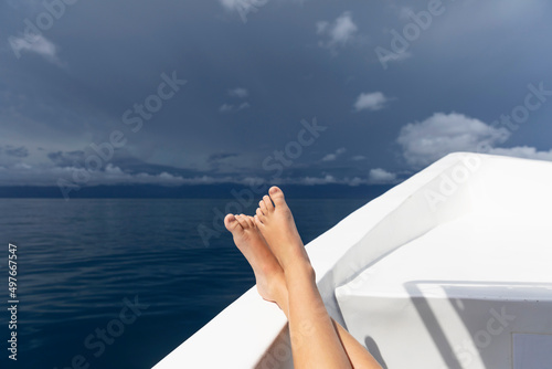 Ocean landscape with bow of boat with barefoot boy relaxing   photo