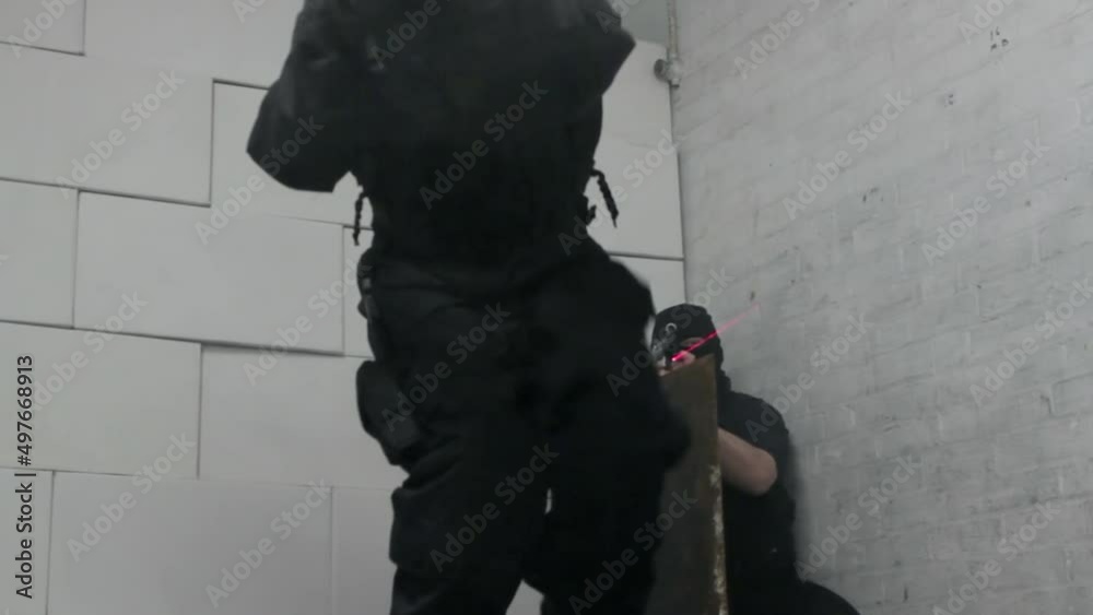 Armed special forces in gas masks and balaclavas enter building through hatch in floor through a tunnel