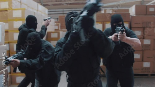 A special forces military team raid a warehouse with guns drawn wearing balaclavas an gas masks photo