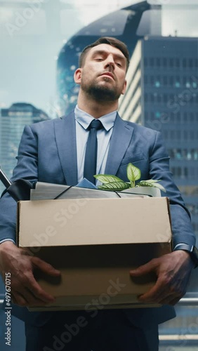 Vertical Screen: Fired Manager Going Down from Office in a Glass Elevator in Modern Business Center. Sad Specialist Laid Off, Feeling Depressed and Devastated, Holding Office Accessories in a Box.