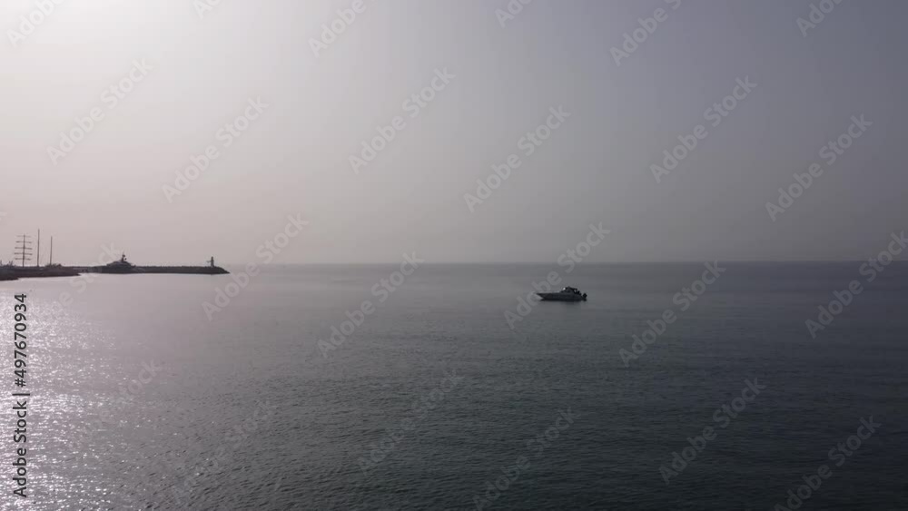 Drone flight over the bay in the rays of dawn. Lonely boat in the Mediterranean sea entering the port of Cyprus. Drone flight over the bay in the rays of dawn. Lonely boat in the Mediterranean sea entering the port of Cyprus.