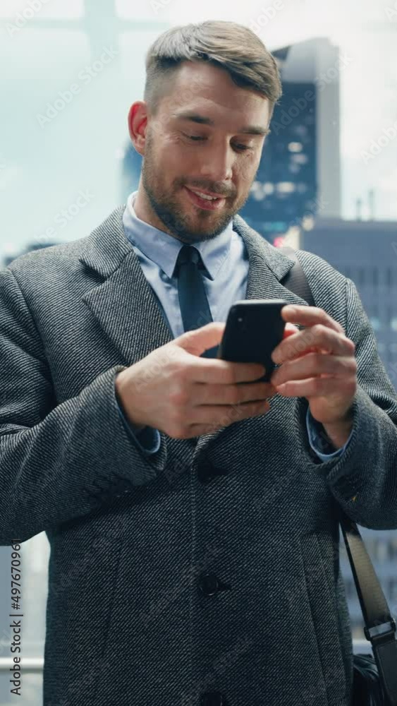 Vertical Screen: Businessman Riding Glass Elevator to Office in Modern Business Center. Handsome Happy Man Smile while Using Smartphone, Write Text Message, Check Social Media and Work Emails in Lift.