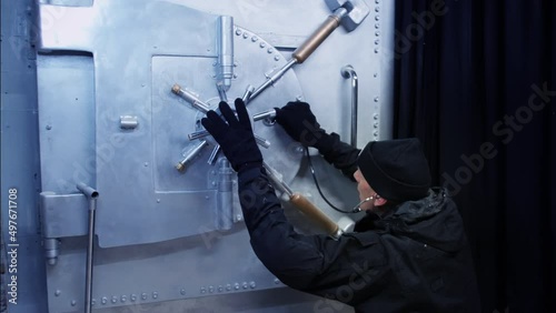 A safecracker breaking into a bank vault. The burglar uses a stethoscope to crack the safe. photo