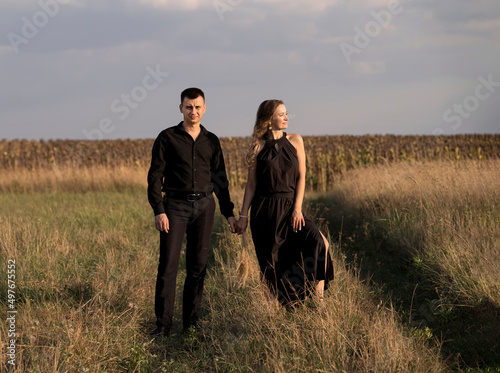 a couple stands in a field in the summer on the grass