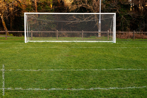 Football or soccer goal post on a green grass pitch in a park. Nobody. Calm mood. Sport theme background. Training ground for outdoor activity photo