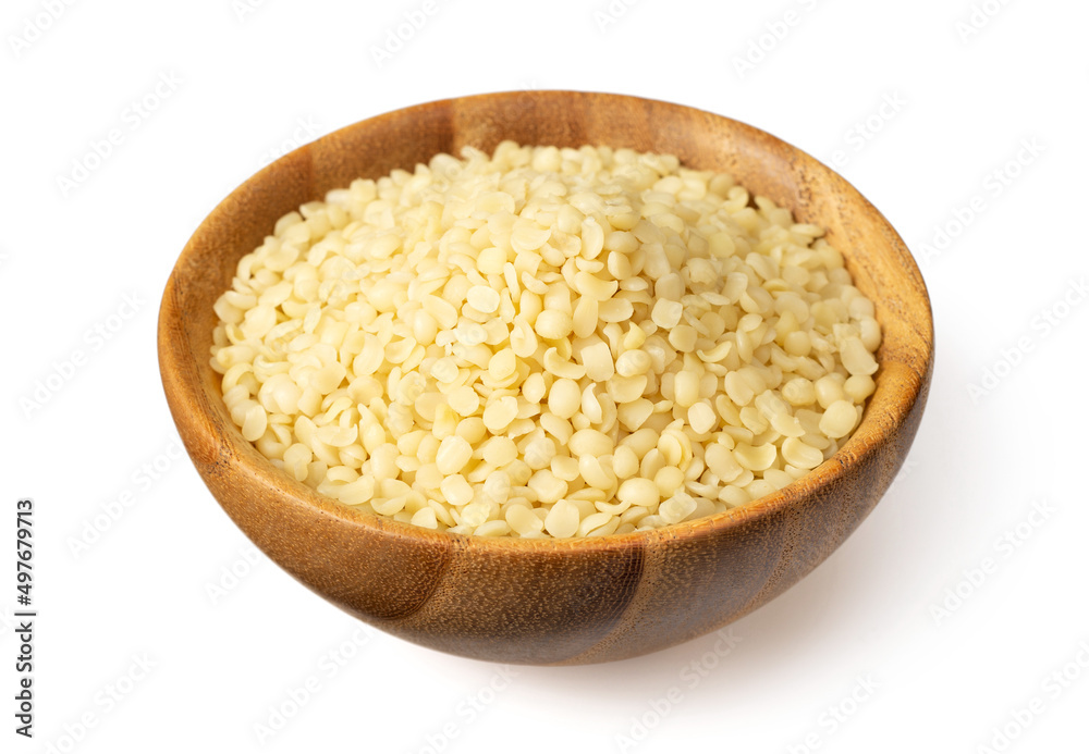Raw hemp seeds in the wooden bowl, isolated on the white background.