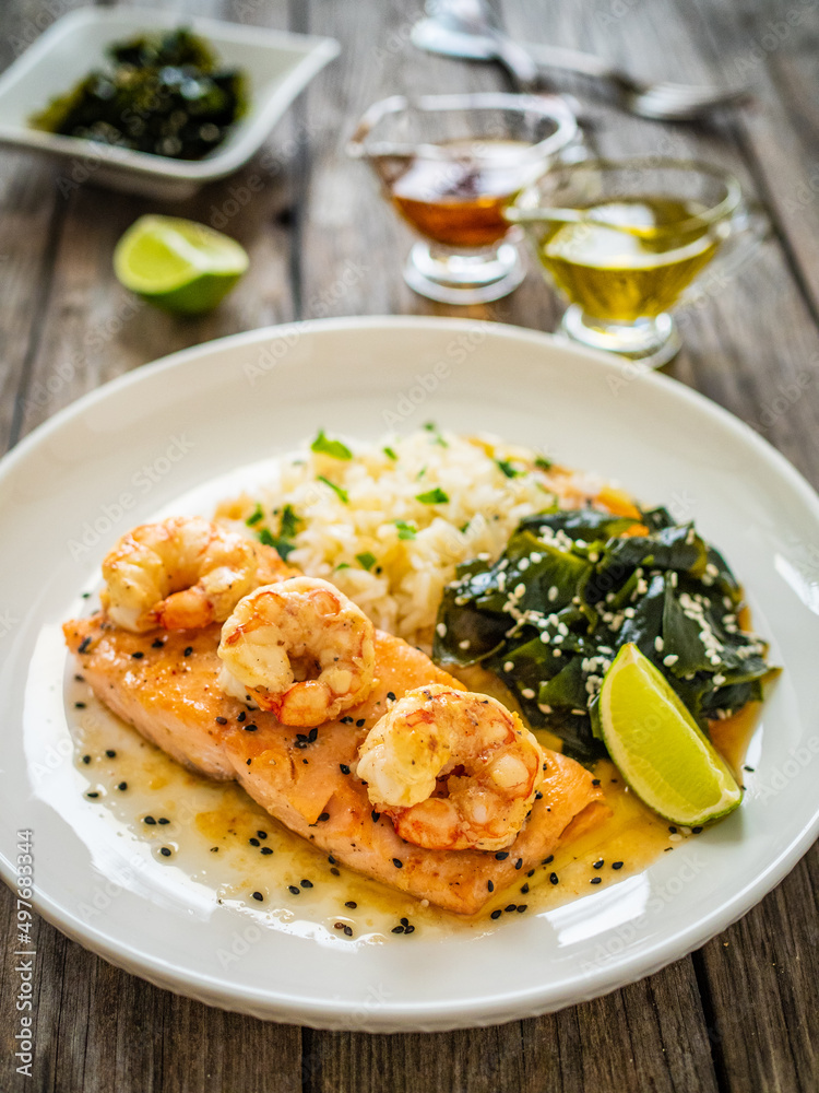 Fried salmon steak with prawns, white rice and spinach on wooden table
Fried salmon steak with prawns, white rice and spinach on wooden table