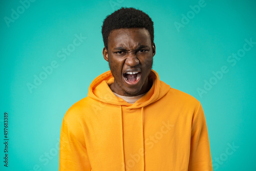 Emotional screaming young african man standing isolated over mint background