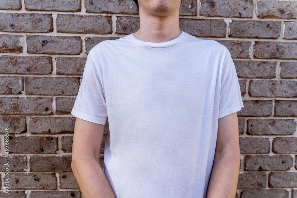Man wearing mockup white t-shirt on brick wall background. Template copy space Man wearing mockup white t-shirt on brick wall background. Template copy space