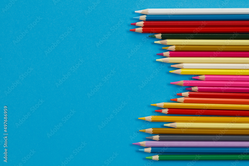 Multi-colored pencils on blue paper. Drawing materials. Multi-colored pencils on blue paper. Drawing materials.