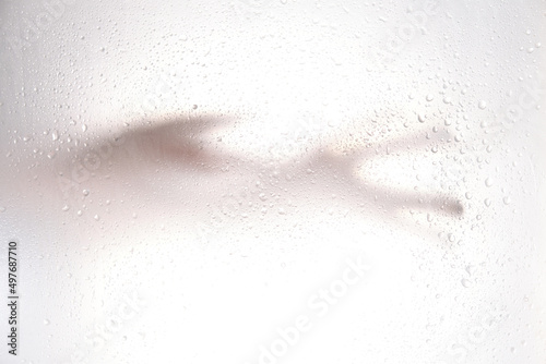 blurred silhouette hand. Grey shadows of one reaching hand on the wall. Abstract blurred effect frosted glass illuminated from behind. © yavdat