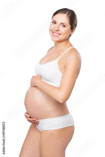 Young pregnant woman in swimsuit. Girl expecting a baby and touching her belly isolated on white background. © Acronym