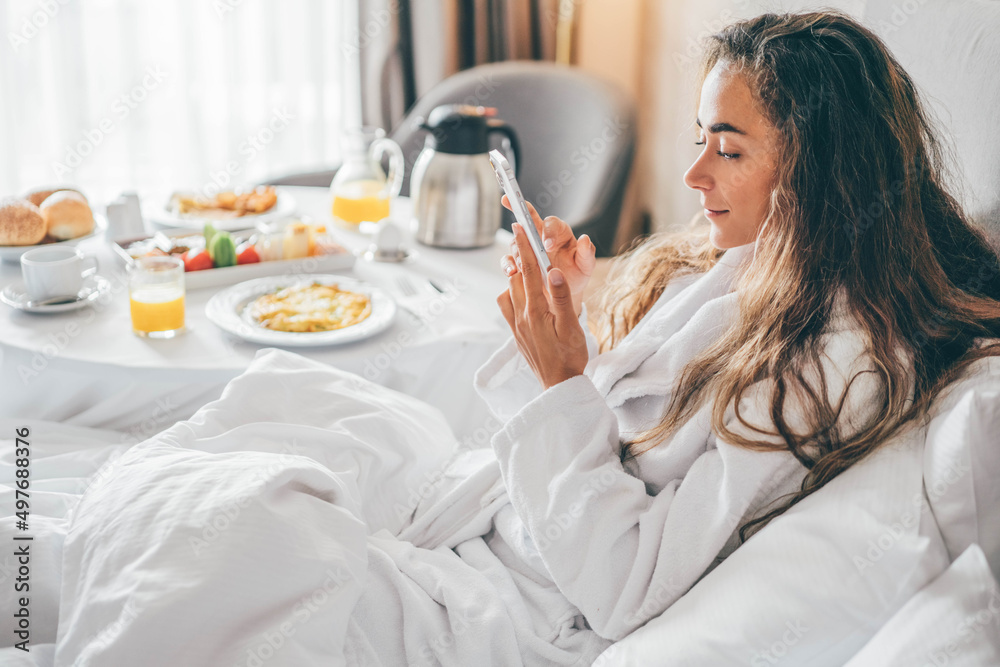 Woman eating breakfast and using phone in the hotel room. Room service  breakfast in hotel room. Stock Photo | Adobe Stock