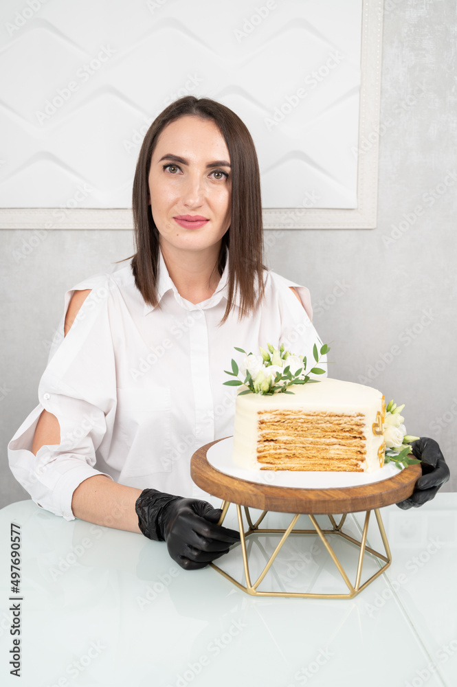 Pastry chef holding tasty wedding cake with floral decoration. Cut cake with visible layers