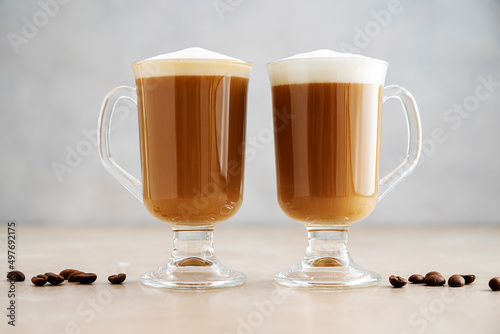 Coffee in glass ?ups with whipped milk foam on neutral background. Copy space for text.