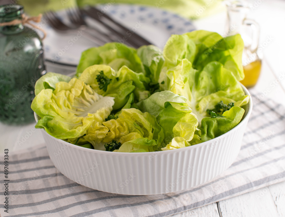 Fresh salad in a bowl with lettuce served as a side dish on white kitchen table Fresh salad in a bowl with lettuce served as a side dish on white kitchen table