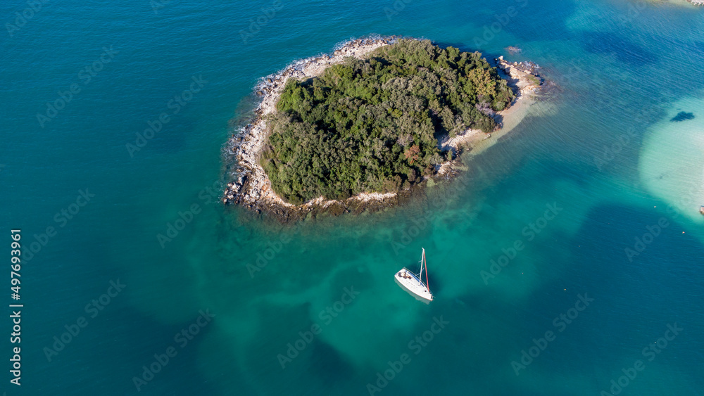 Aerial drone view of the beautiful seaside coast on a sunny day. Marvelous blue colors. Holidays and relaxing mood. Islands and boats. Amazing beaches to mediate and cure the soul. Vibrant colors.
