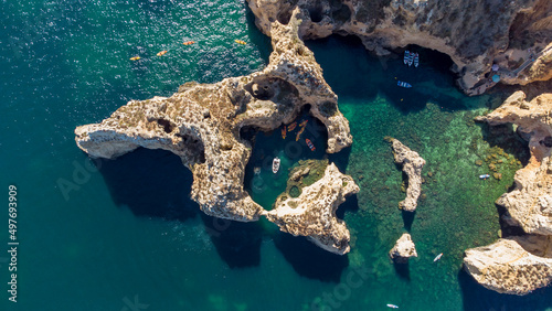 Amazing scenic drone aerial view of the beach and ocean with calm waves during a sunset with vibrant colors. Algarve, Portugal. Clear waters. Holidays and Vacations. Background. Beach with rocks. 