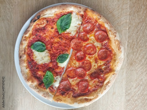 Half a salami pizza and half Margherita pizza with mozzarella, tomato sauce and basil. Fresh and crispy.Italian specialty - Salami Pizza and Margherita pizza with mozzarella, tomato sauce and basil. 