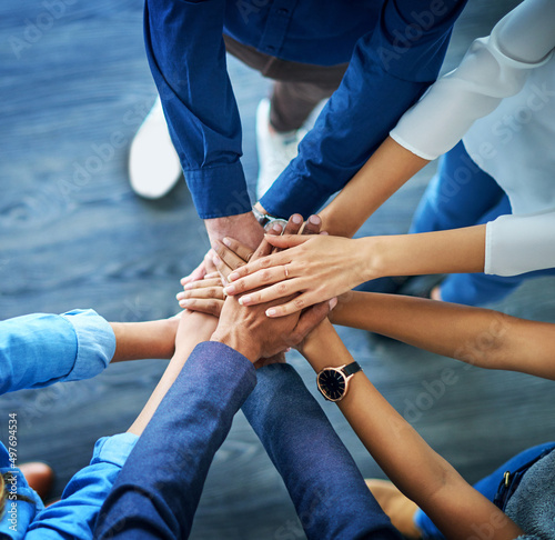 Lets awaken the team spirit. High angle shot of a group unrecognizable businesspeople joining their hands together in unity. photo
