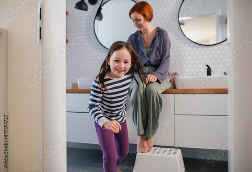 Mother with her little daughter in bathroom at home.