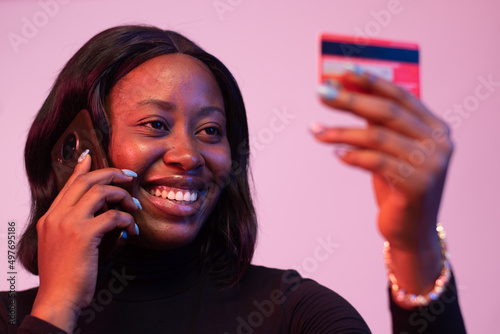 african lady holding a credit card and making a phone call