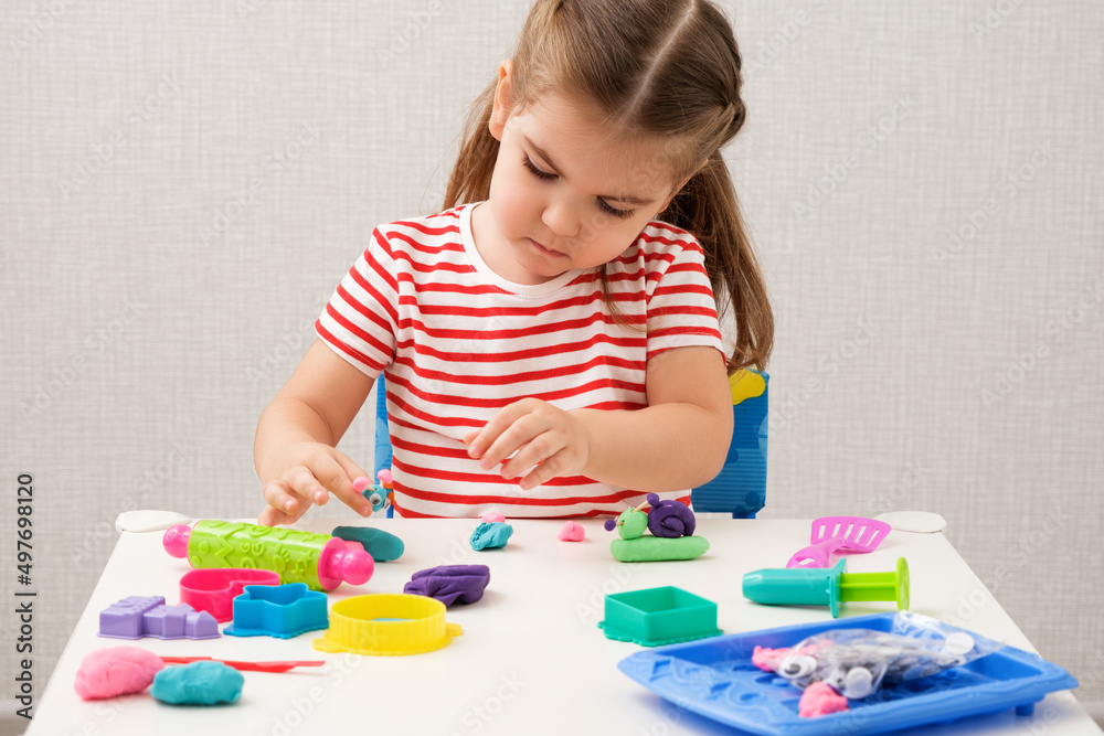 little girl enthusiastically plays with plasticine, play dough on white table at home, children's creativity little girl enthusiastically plays with plasticine, play dough on white table at home, children's creativity