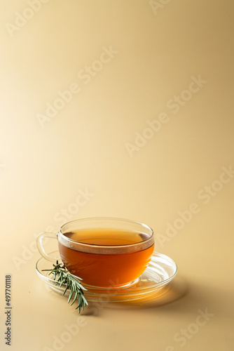 Herbal rosemary tea in a glass cup and fresh rosemary banch on beige background. healthe beverage . Copy space