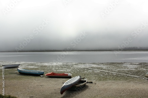 Boats on a beach during low tide in a misty morning photo