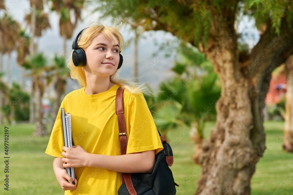 Outdoor portrait of teenage female student in headphones with laptop backpack Outdoor portrait of teenage female student in headphones with laptop backpack