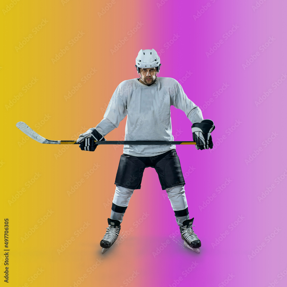 Professional ice hockey player hitting puck for winning goal in action on gradient multicolored neon background. Concept of sport competition. Professional ice hockey player hitting puck for winning goal in action on gradient multicolored neon background. Concept of sport competition.