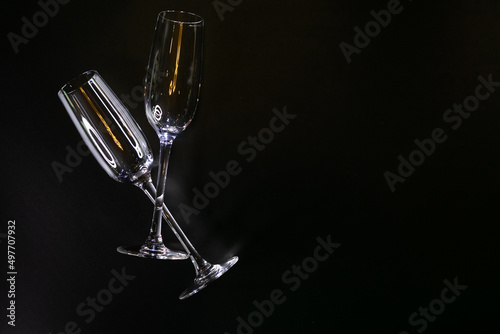 Two glasses of champagne lie on a black background