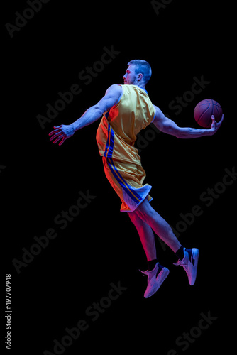 Fototapeta Naklejka Na Ścianę i Meble -  Portrait of sportive man, professional basketball player playing basketball isolated on dark background in neon light. Achievements, sport career, motion concepts.