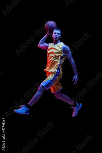 Portrait of sportive man, professional basketball player playing basketball isolated on dark background in neon light. Achievements, sport career, motion concepts. © master1305