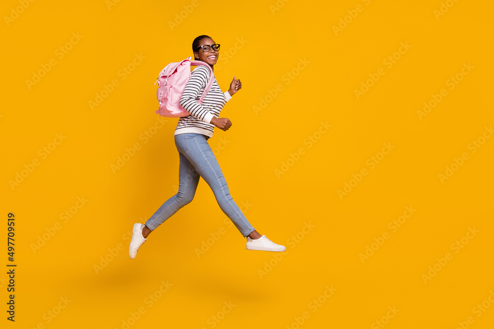 Full size profile side photo of young girl walk jump academic courses isolated over yellow color background