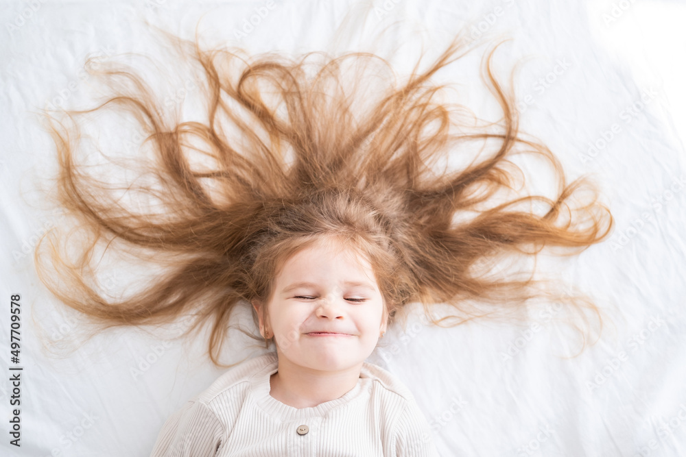 portrait of child girl with blonde long hair in pajamas lying in bed in the morning portrait of child girl with blonde long hair in pajamas lying in bed in the morning