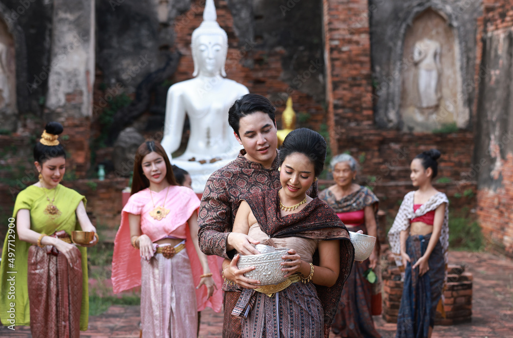 Naklejka premium Asia group peple wearing Thai Traditonal dress plash water to each other , celebrate Songkran festival at Choengthar Temple , Ayuthaya of Thailand